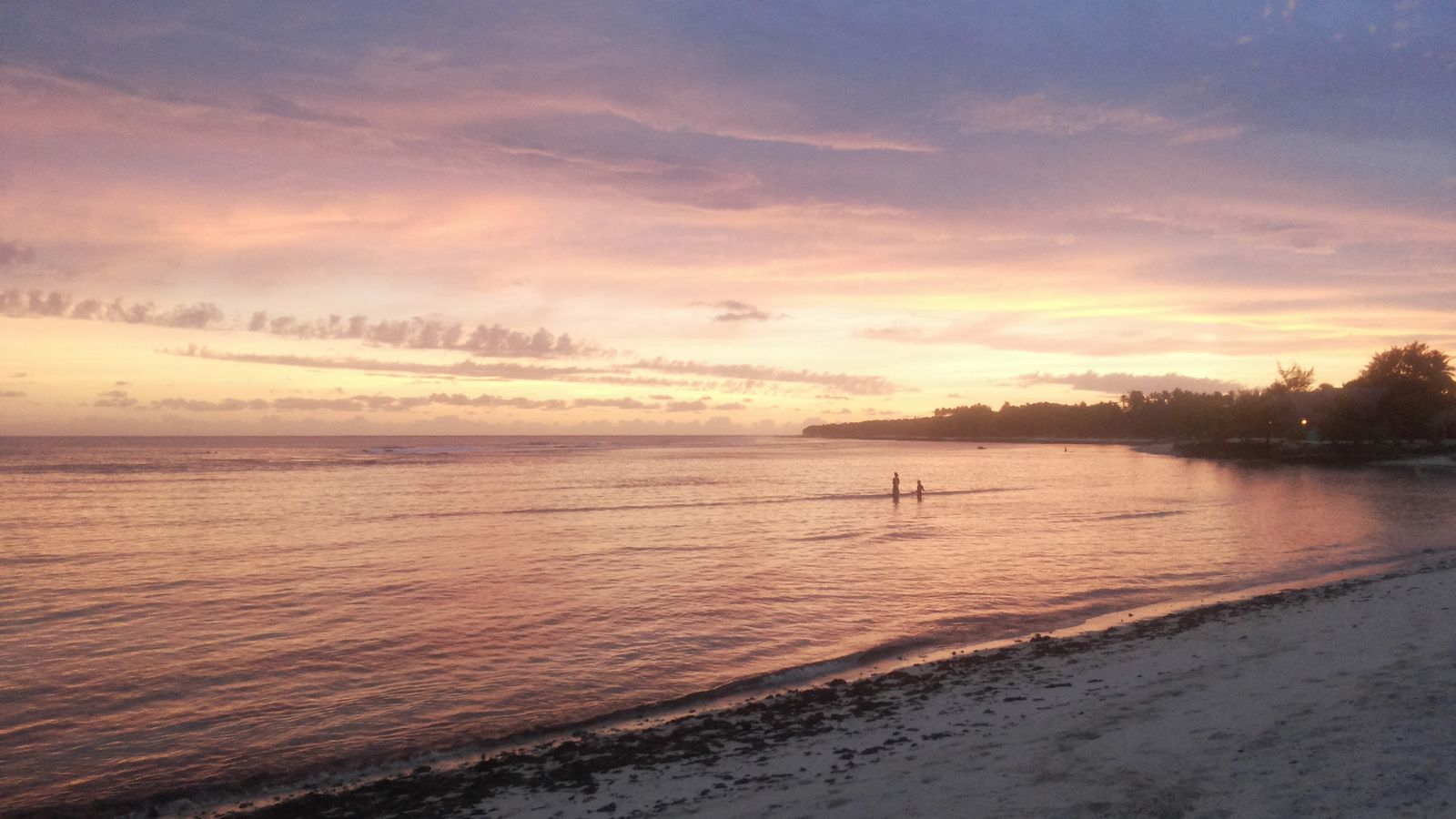 Pink and orange sunset over the lagoon at Pango with the reef break in the distance